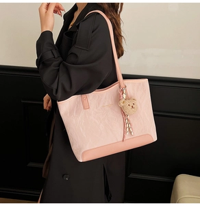 Detail view of pink tote bag with leather texture and cute brown plush bear charm