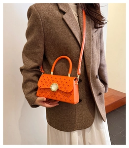 Détail du sac à main orange vif matelassé avec rivets et boucle ronde type bijou