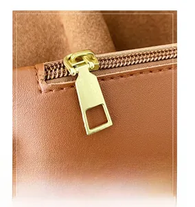 Detail of smooth gold-tone zipper and premium caramel suede leather texture on tote bag