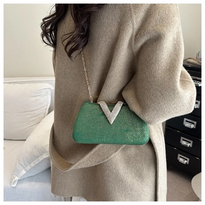 Detail of green box evening clutch with sparkling V-shaped rhinestone buckle and gold chain