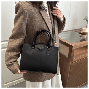 Close-up of elegant black lychee pattern leather handbag with gold hardware details