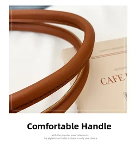 Detailed close-up of brown suede tote bag handles with precise stitching and leather texture