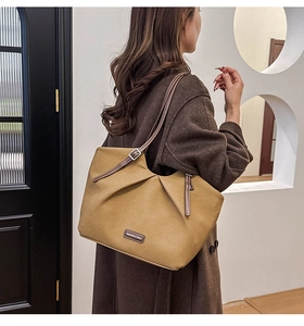 Close-up of khaki canvas tote bag with brown leather straps and fashion label tag