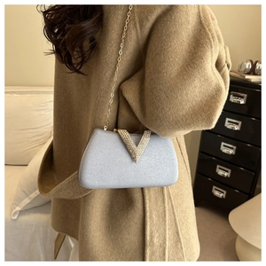 Detail view of light blue box clutch with gold V-buckle and rhinestone chain strap