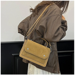 Detail of mustard yellow and tan handbag with silver buckle shown by a model