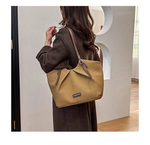 Detail of khaki pleated tote bag with leather straps and Fashion label on a model