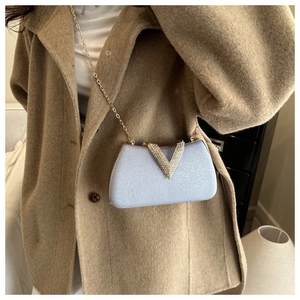 Detail of light blue glitter clutch bag with V-shaped rhinestone buckle and gold chain strap
