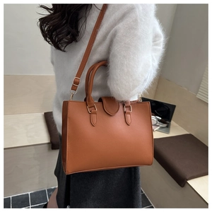 Borsa a mano in pelle martellata color caramello indossata a spalla da una modella