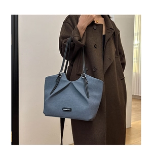 Detailed view of dark blue pleated tote bag with black leather strap and textured fabric