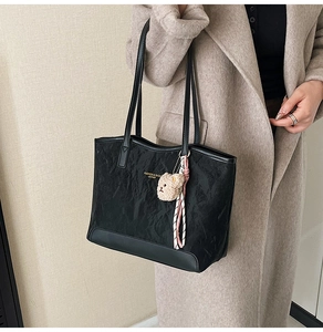 Close-up of black leather tote bag featuring pleated texture and gold lettering