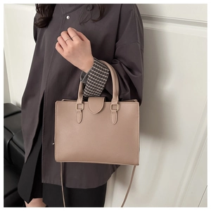 Detail of taupe leather tote bag with gold hardware and reinforced dual handles