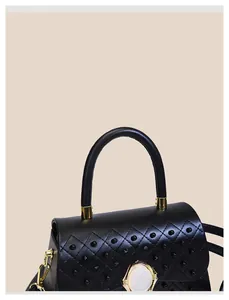 Détail de sac à main en cuir noir matelassé avec rivets dorés et boucle en pierre
