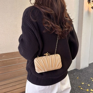 Elegant gold pleated satin evening clutch bag with bird-shaped clasp and chain strap