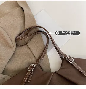 Detail of canvas tote bag showing dark brown fabric texture and leather handle with silver buckle