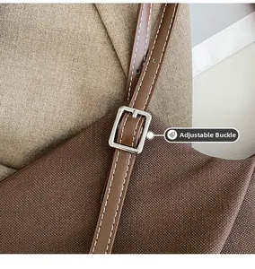 Detail of adjustable brown leather strap with silver metal buckle on a canvas tote bag