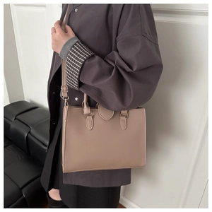 Detail of a beige PU leather tote bag with lychee grain texture and a crossbody strap