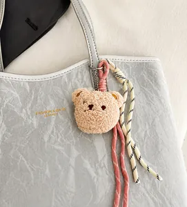 Close-up of a cute plush bear bag charm with woven rope detail on a leather tote