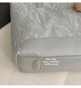 Detail of silver tote bag base with anti-slip studs and reinforced grey leather panel
