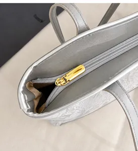 Detail of smooth gold zipper hardware and silver leather texture on a retro tote bag
