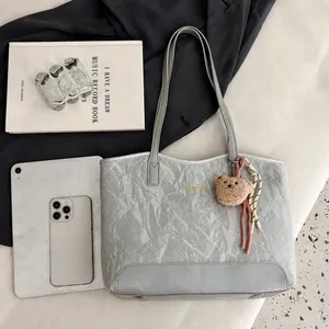 Detailed view of silver grey tote bag with crinkled texture, bear charm and spacious interior