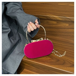 Close-up of rose red velvet handbag with gold metal bow clasp and handle on wooden stairs