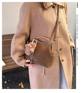 Détails du sac coquille en daim marron avec poignée en métal et breloque ours