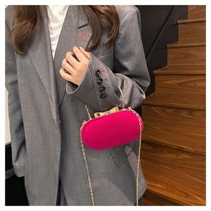 Detail of rose red velvet evening clutch bag with gold bow clasp and metal chain strap