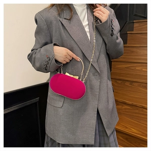 Fuchsia velvet evening bag with gold handle and chain on a stylish model