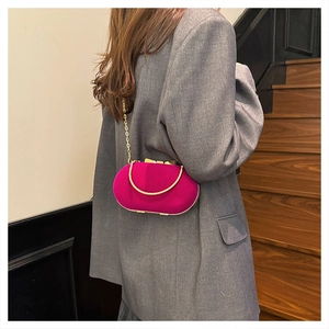 Close-up of fuchsia velvet evening clutch bag with gold chain strap on model