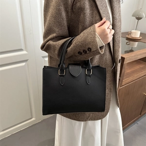 Elegant black lychee grain tote bag with gold hardware shown on model for office wear