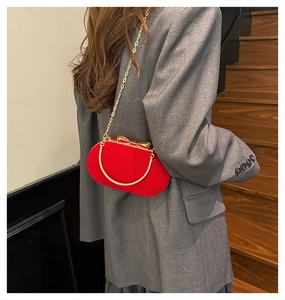 Close-up of red velvet evening bag featuring gold bow clasp and metallic handle