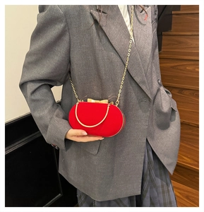 Detail of red velvet evening bag featuring gold bow metal clasp and chain strap