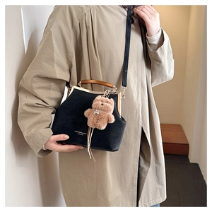 Sac bandoulière rétro noir avec poignée en bois et peluche ours sur trench beige
