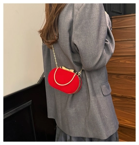 Detail of red velvet evening bag with gold bow clasp and sleek chain strap for women