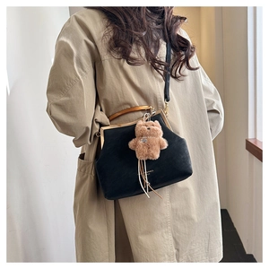Détail du sac vintage noir avec poignée ambrée et pendentif ours porté par le mannequin
