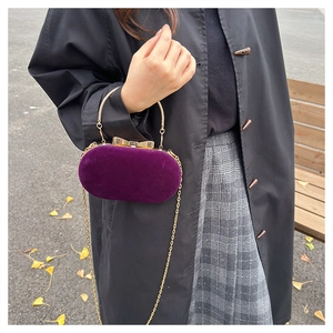 Detail of velvet evening bag with gold bow clasp and metallic handle in autumn setting