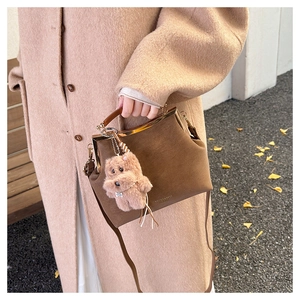 Détail du sac vintage en daim marron foncé avec fermoir métallique et pendentif ours