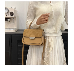 Detail of contrast stitching and texture on a stylish two-tone saddle bag with metal clasp