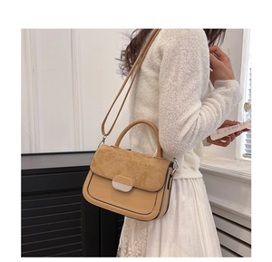 Detailed close-up of retro color-block handbag with khaki leather and tan suede textures