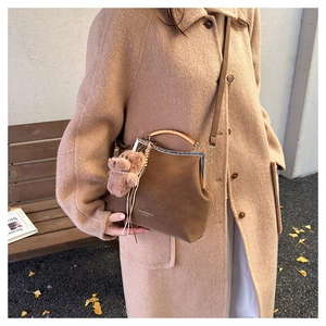 Gros plan d'un sac vintage marron avec charm ours en peluche dans un décor d'automne