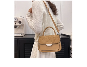Detail view of a brown saddle bag with suede flap and silver lock on a female model