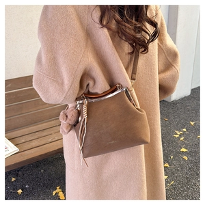 Détail du sac vintage marron avec pompon en peluche et cadre en métal doré