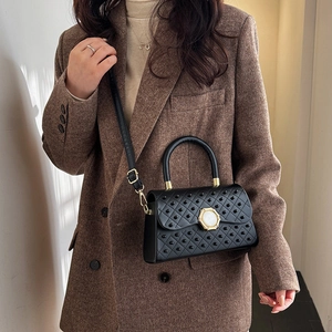 Sac à main noir élégant à perles avec boucle dorée porté par un mannequin chic