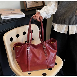 Detail of burgundy vintage tote bag featuring white contrast stitching and silver rivets