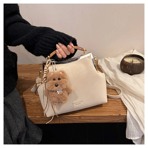 Détail d'un sac vintage crème avec poignée en bois et pendentif ours en peluche