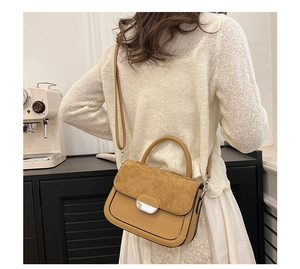Close-up of contrast stitching and silver metal buckle on suede saddle bag detail