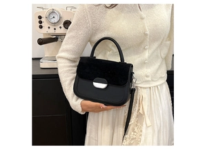Detail of black saddle bag with suede flap and silver buckle on an elegant outfit