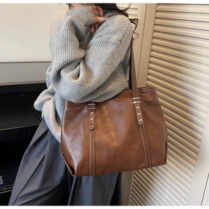 Detail of vintage brown tote bag with silver studs and white contrast stitching