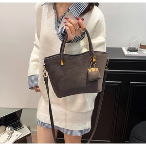Detail of dark brown suede tote bag with gold hardware, mini coin purse and shoulder strap