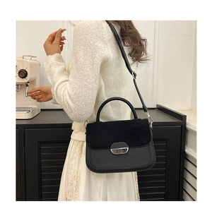 Detail of black crossbody saddle bag showing smooth leather and suede flap texture
